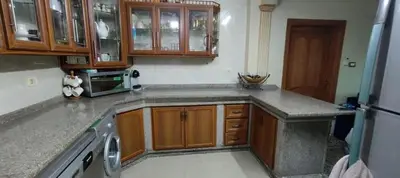 a kitchen with wooden cabinets and a dishwasher at sliver apartment in Bayt Raʼs