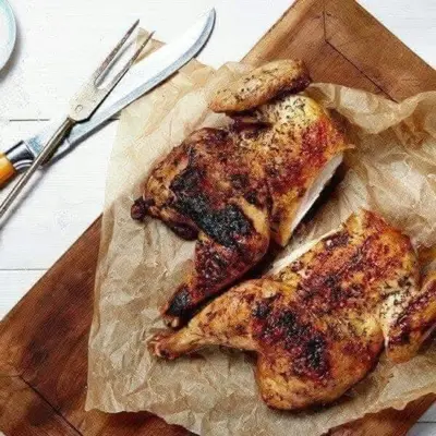 two pieces of chicken on a cutting board with a knife at sliver apartment in Bayt Raʼs