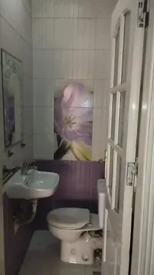 a bathroom with a toilet and a flower on the wall at rafat house in Amman