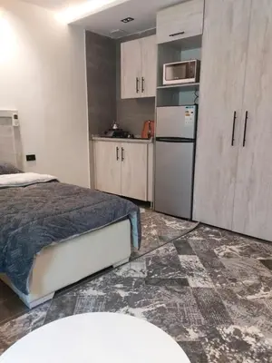 a bedroom with a bed and a refrigerator and cabinets at رياحين الخلود للشقق الفندقية in Amman