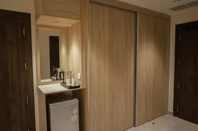 a kitchen with wooden cabinets and a small refrigerator at ISHQ Hotel in Aqaba