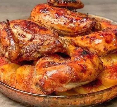 a plate of chicken and potatoes on a table at too house in Al Mughayyir