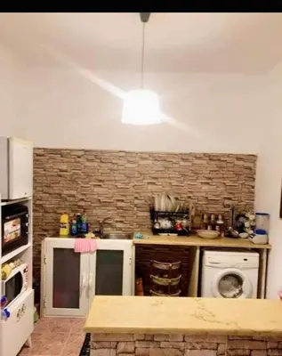 a kitchen with a brick wall and a white appliance at too house in Al Mughayyir
