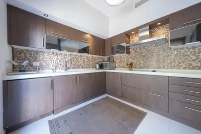 a large kitchen with wooden cabinets and a rug at Tower Apartment in Amman
