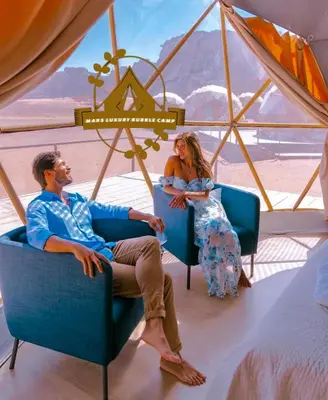 a man and woman sitting in chairs in a tent at RUM MARS BUBBLE lUXURY CAMP in Wadi Rum