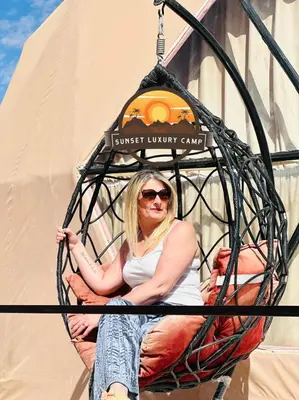 a woman is sitting in a hanging basket at RUM SUNSET BUBBLES lUXURY CAMP in Wadi Rum