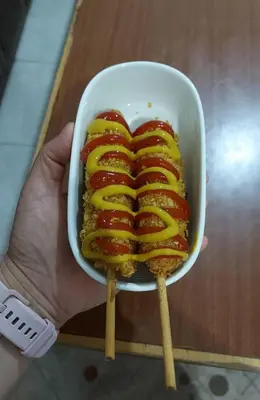 a person holding a sandwich with mustard and ketchup at الخريطه هاوس in Tall al Misţāḩ