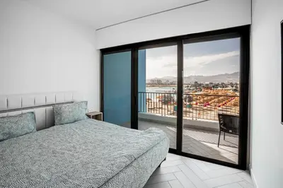 a bedroom with a bed and a balcony with a view at Ayla B12 Beach Apartment Aqaba in Aqaba