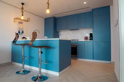 a kitchen with blue cabinets and two bar stools at Ayla B12 Beach Apartment Aqaba in Aqaba