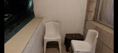 two white chairs and a table and a window at بيت الحجر in Amman