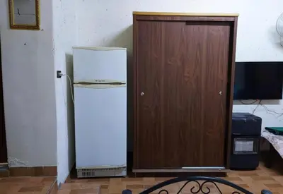 a white refrigerator next to a wooden door at بيت الحجر in Amman