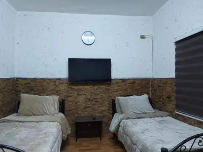 a room with two beds and a tv on the wall at بيت الحجر in Amman
