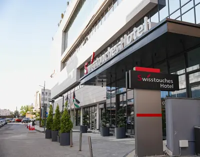 a building with a sign in front of it at Swisstouches Hotel Amman in Amman