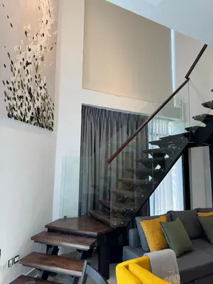 a living room with a staircase and a couch at DAMAC Pool View Penthouse in Amman