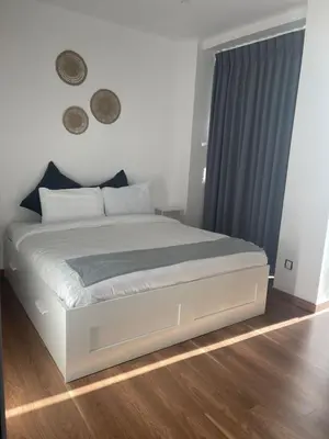 a bedroom with a white bed with blue curtains at DAMAC Pool View Penthouse in Amman