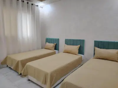 two beds in a room with white walls at Al Wesam Furnished Apartments in Aqaba