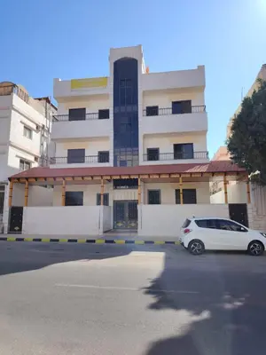 a white car parked in front of a building at Al Wesam Furnished Apartments in Aqaba