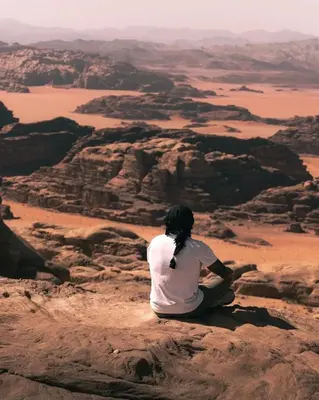 a woman sitting on a rock in the desert at Wadi Rum Thamer in Wadi Rum