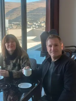 a man and woman sitting at a table with a cup of coffee at Mountain Echo Inn in Taiyiba