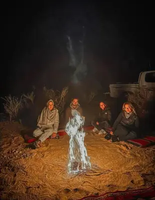 a group of people sitting around a fire at Wadi Rum sleeping in the desert in Wadi Rum