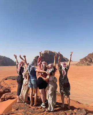 a group of people standing on a rock in the desert at Wadi Rum sleeping in the desert in Wadi Rum