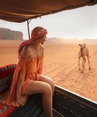 a woman sitting on a camel in the desert at Wadi Rum sleeping in the desert in Wadi Rum