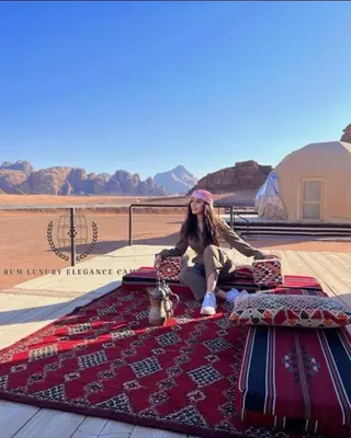 a woman sitting on top of a rug on top of a bed at RUM ELEGANCE BUBBLE lUXURY CAMP in Wadi Rum