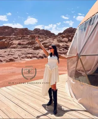 a woman in a white dress and boots on a boardwalk at RUM ELEGANCE BUBBLE lUXURY CAMP in Wadi Rum
