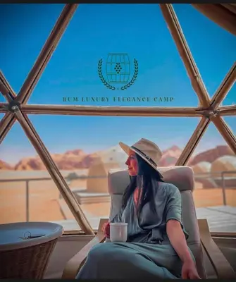 a woman sitting in a chair with a cup of coffee at RUM ELEGANCE BUBBLE lUXURY CAMP in Wadi Rum