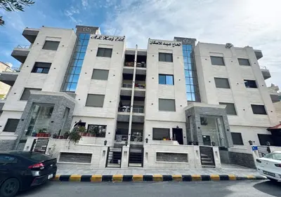 a large building with cars parked in front of it at Sweet Home In Amman - Family Friendly in Amman
