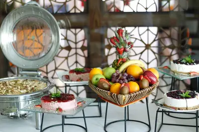 a table with a bowl of fruit and cakes on plates at Meneur Hotel in Amman