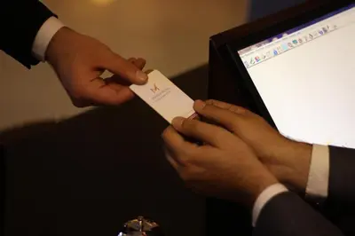 a man handing another man a piece of paper at Meneur Hotel in Amman