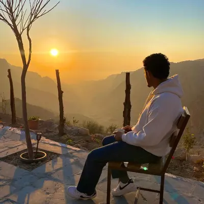 a man sitting in a chair watching the sunset at Dana Trail Hotel in Dana