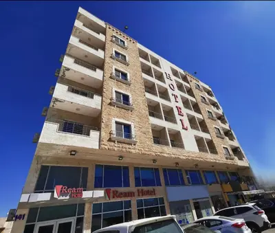 a tall building with cars parked in a parking lot at Ream Hotel Amman in Amman