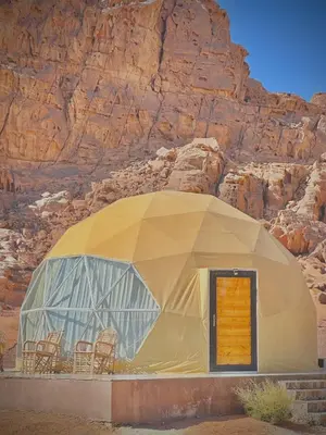 a dome house with chairs in front of a mountain at RUM CAMILLA lUXURY CAMP in Wadi Rum