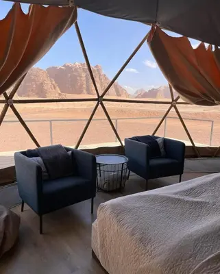 a room with two chairs and a bed and a view of a desert at RUM CAMILLA lUXURY CAMP in Wadi Rum