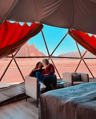 two people sitting in a tent looking out at the desert at RUM CAMILLA lUXURY CAMP in Wadi Rum