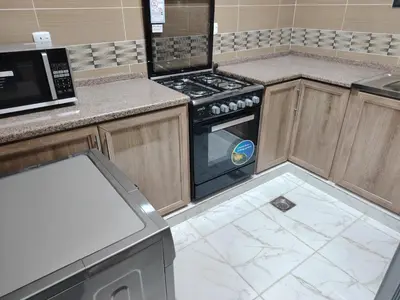 a kitchen with a stove and a microwave at Al Wesam Furnished Apartments in Aqaba