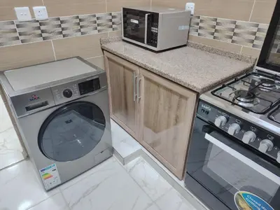 a kitchen with a microwave and a washing machine at Al Wesam Furnished Apartments in Aqaba