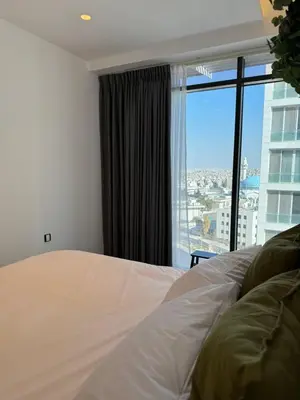 a bedroom with a bed and a large window at DAMAC City View Penthouse in Amman