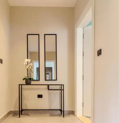 a room with three mirrors and a table with flowers on it at Flamant Apartments in Amman