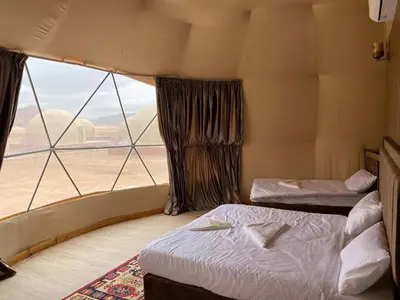 a room with two beds and a large window at Laurana Rum Luxury Camp in Wadi Rum