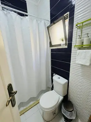 a bathroom with a white toilet and a window at White Apartment in Aqaba