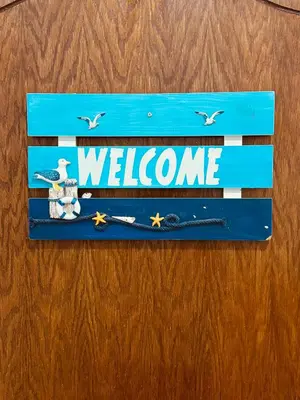a blue welcome sign on a wooden door at White Apartment in Aqaba