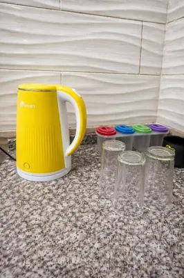 a yellow coffee mug and three glasses on a counter at White Apartment in Aqaba