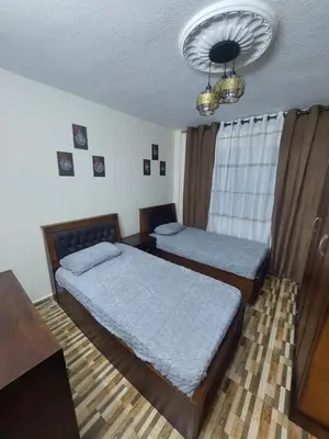 a bedroom with two beds and a chandelier at New zarqa in Az Zarqa