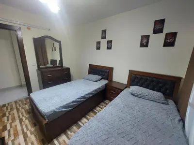 a bedroom with two beds and a dresser and a mirror at New zarqa in Az Zarqa