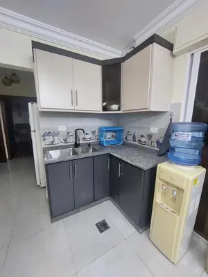 a kitchen with white cabinets and a sink and a refrigerator at New zarqa in Az Zarqa
