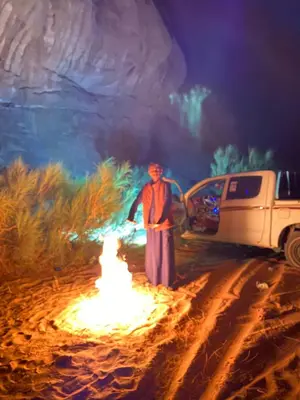 a painting of a man standing next to a fire at Green Desert in Wadi Rum