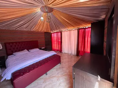 a bedroom with a large bed with red curtains at Rum Experience in Aqaba